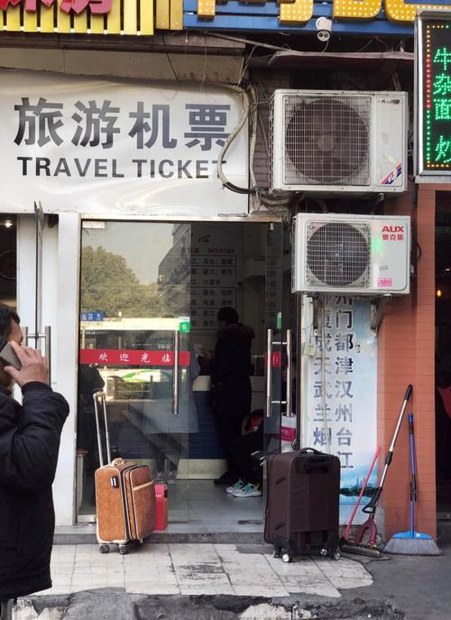 "旅游机票"招牌的票务代理门店内,几名旅客正在购票,其中一人手铸正